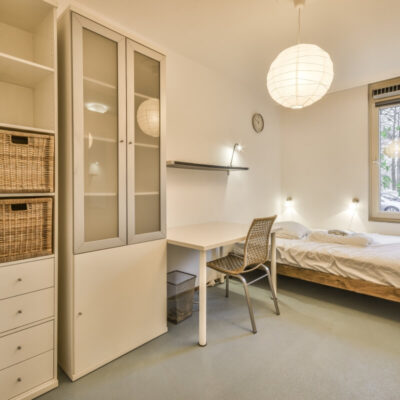 Jasny pokój z łóżkiem, biurkiem i nowoczesnymi rozwiązaniami w zakresie izolacji termicznej.