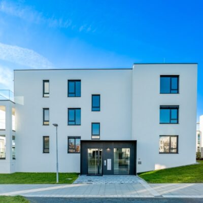 Nowoczesny, biały budynek mieszkalny ilustrujący budownictwo pasywne i energooszczędne.