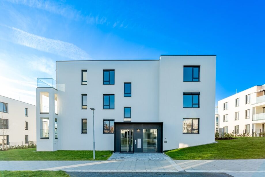 Nowoczesny, biały budynek mieszkalny ilustrujący budownictwo pasywne i energooszczędne.